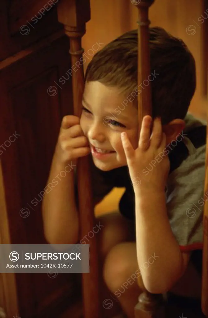 Boy peeking through a wooden banister