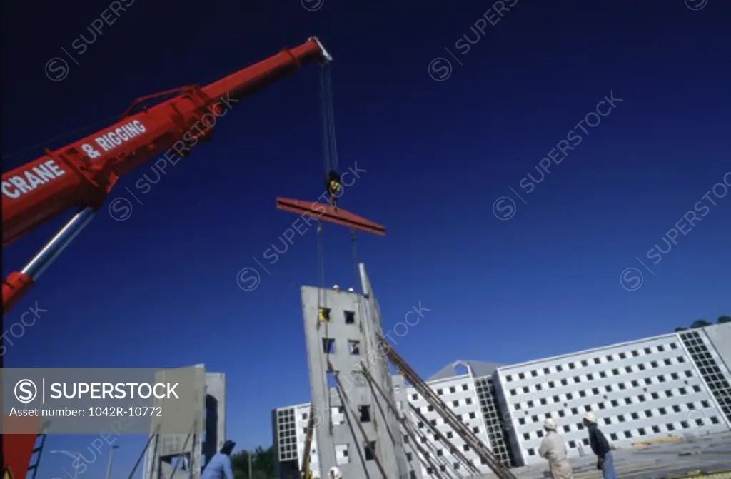 Low angle view of a crane carrying a section of a building