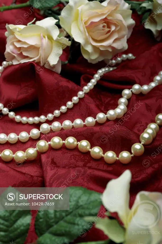 Close-up of a pearl necklace and roses