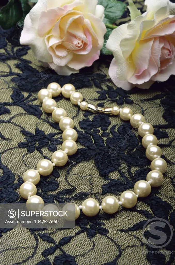 Close-up of a pearl necklace and roses
