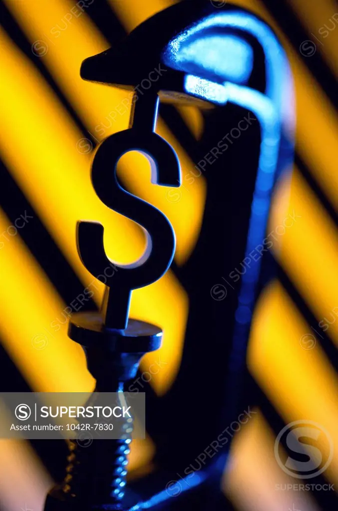 Dollar sign between the jaws of a clamp