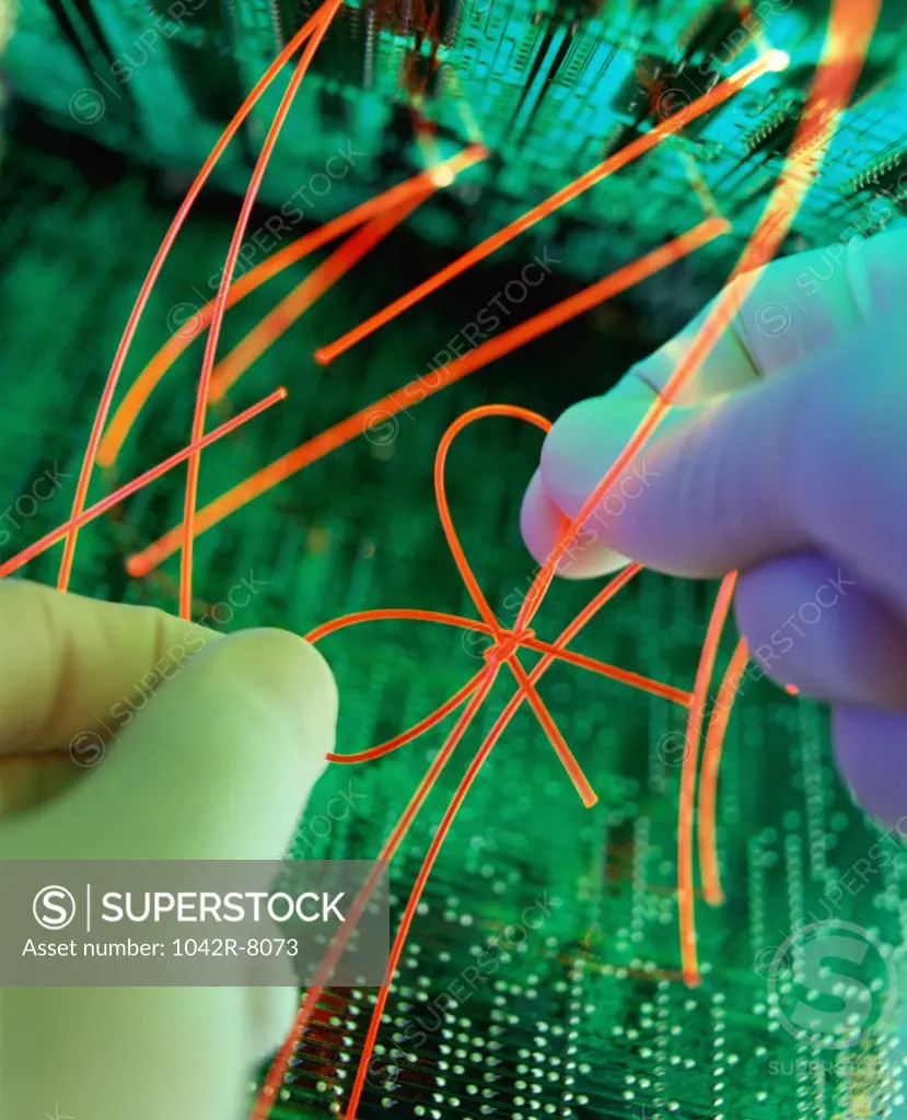 Close-up of a person's hands tying a bow over a circuit board