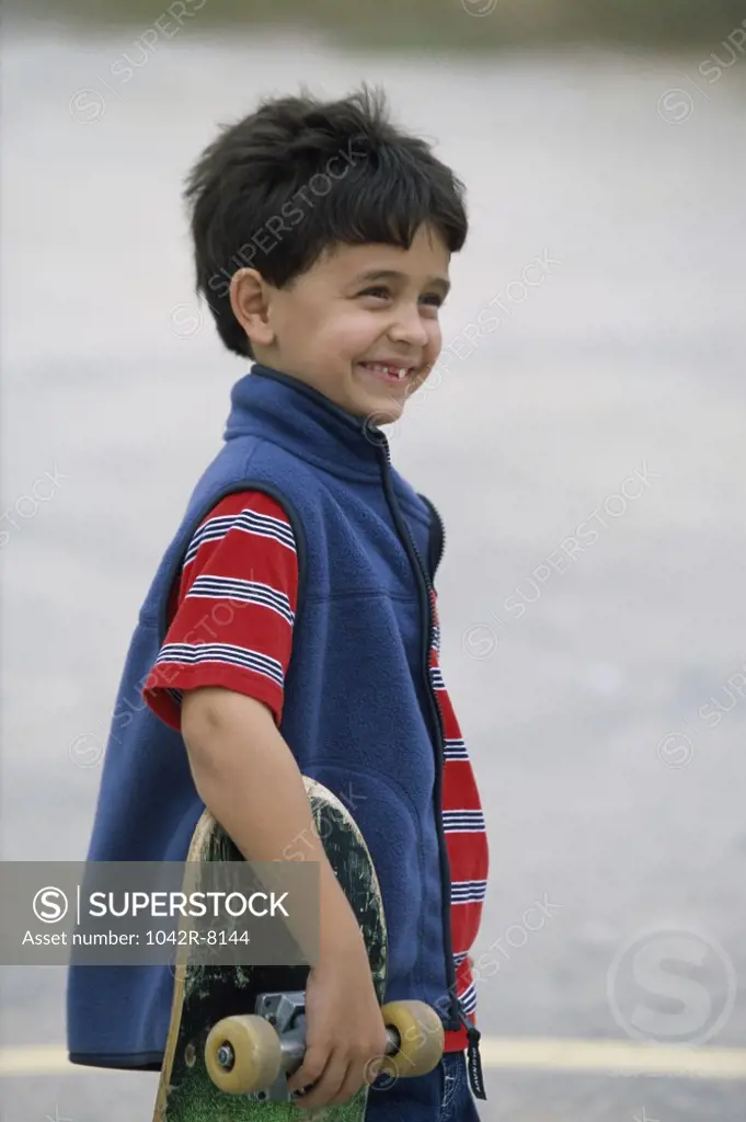 Side profile of a boy holding a skateboard