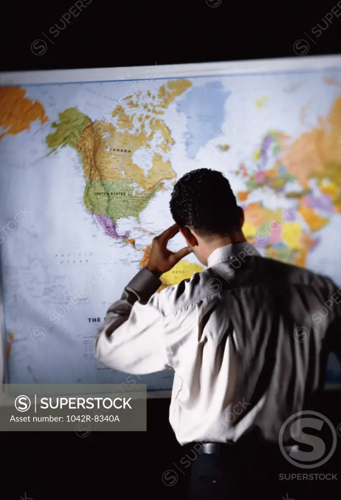 Rear view of a businessman in front of a map