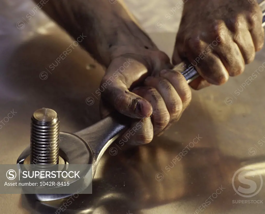 Person's hand holding a spanner on a nut