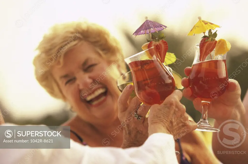 Three senior women toasting with cocktails