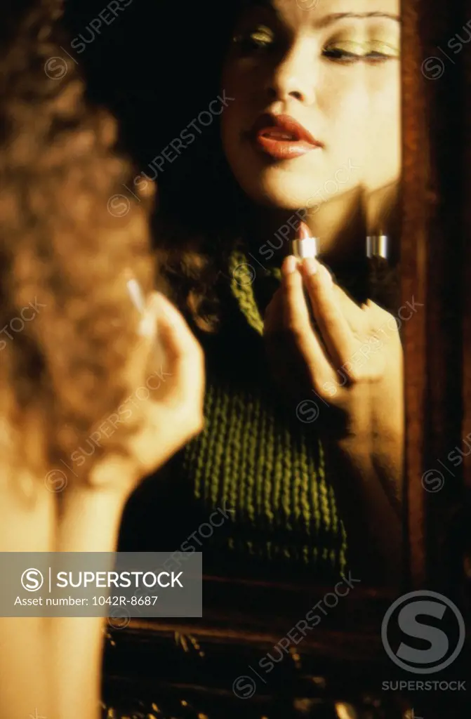 Reflection of a young woman applying lipstick