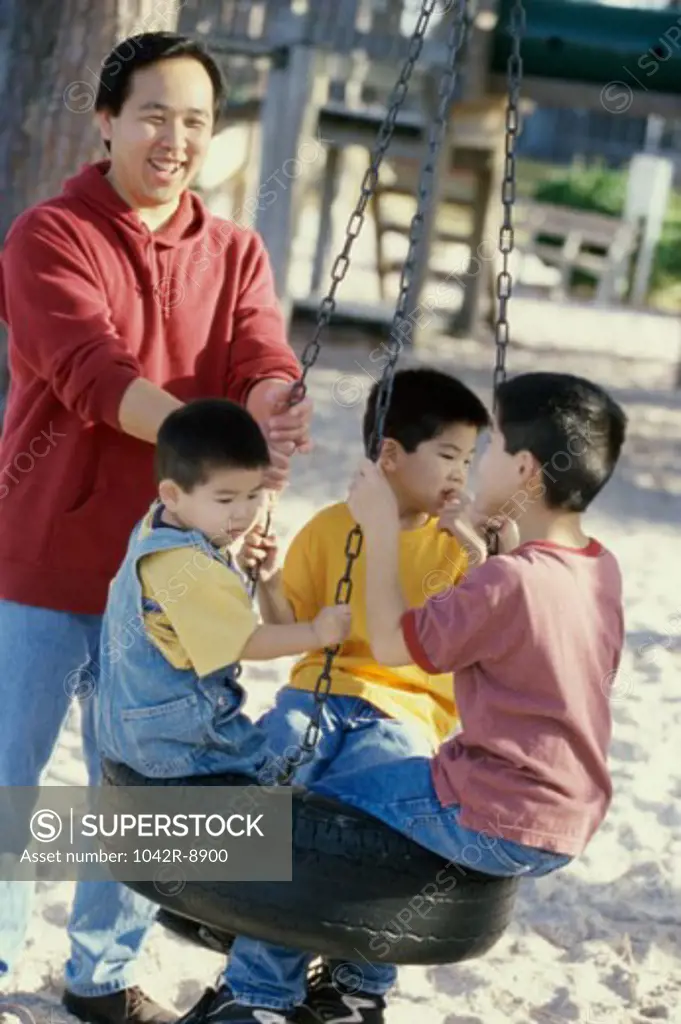 Father playing with his three sons on a swing