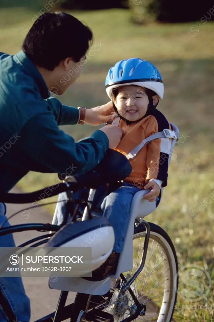Father fastening the strap of a cycling helmet on his daughter