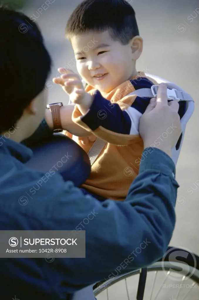 Father strapping his son on a bicycle