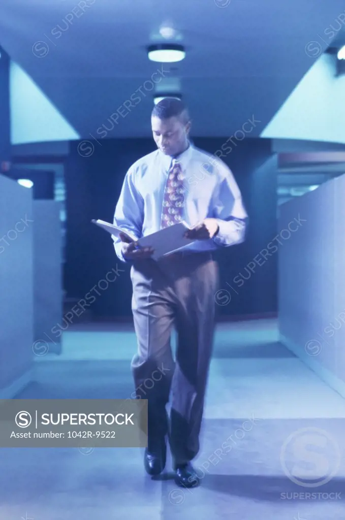 Businessman walking in a corridor reading a file