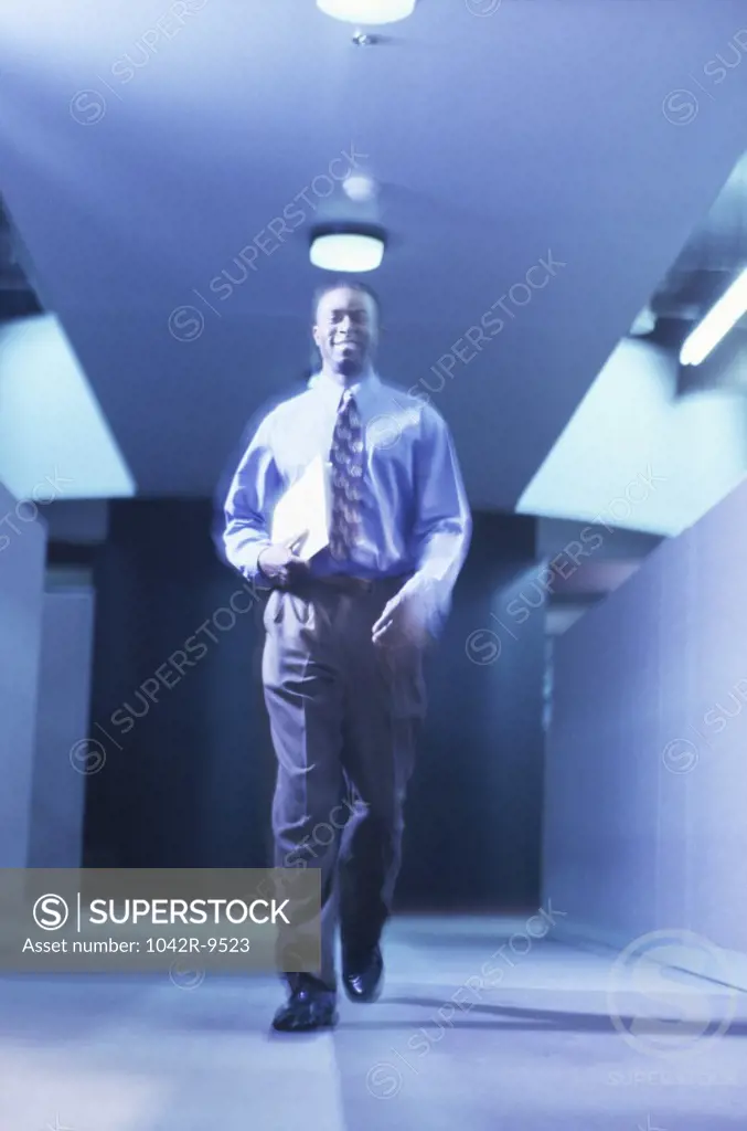 Businessman walking in a corridor holding a file