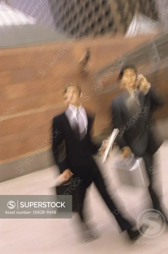 Two businessmen walking holding briefcases