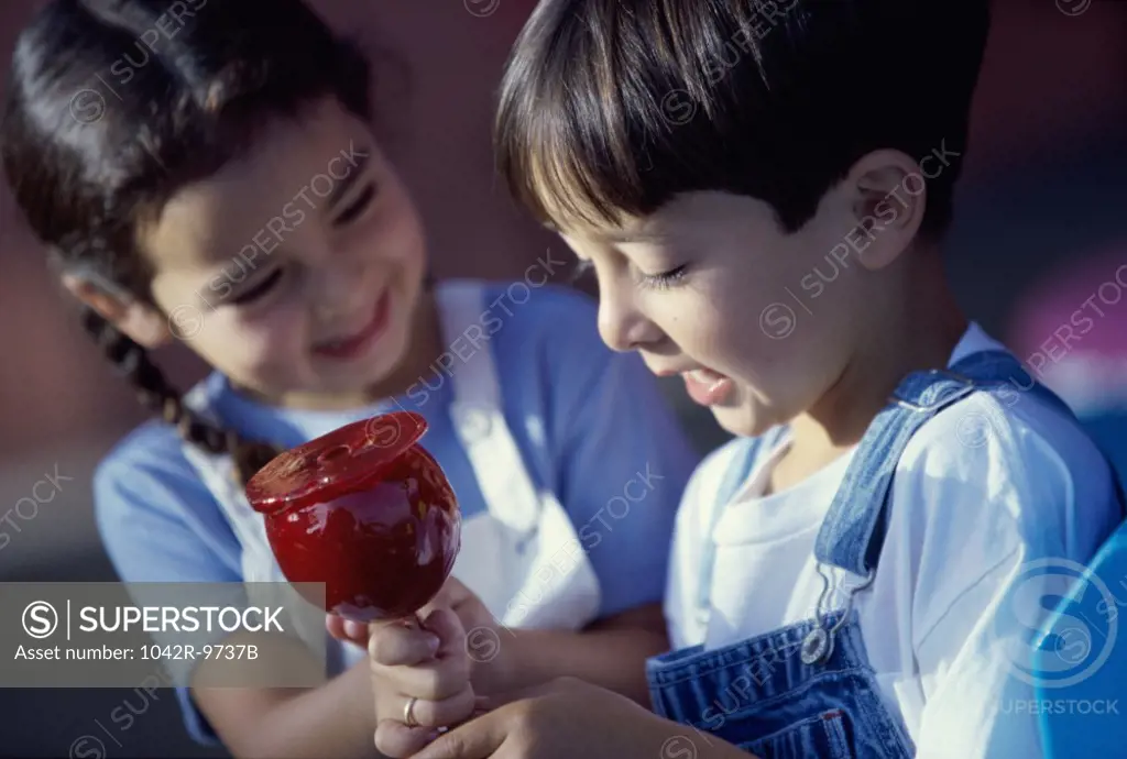 Girl and a boy sitting together holding a candy apple