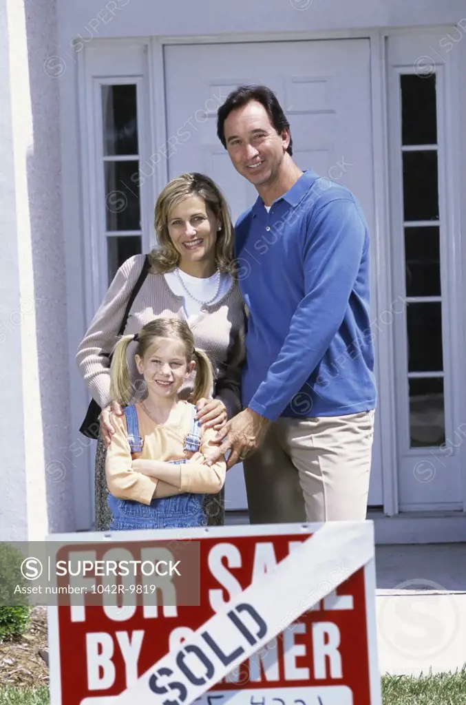 Family standing in front of a house with a sold sign