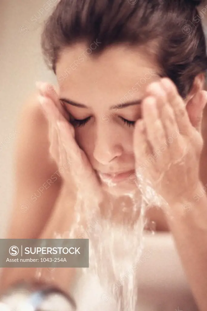 Close-up of a young woman splashing water on her face