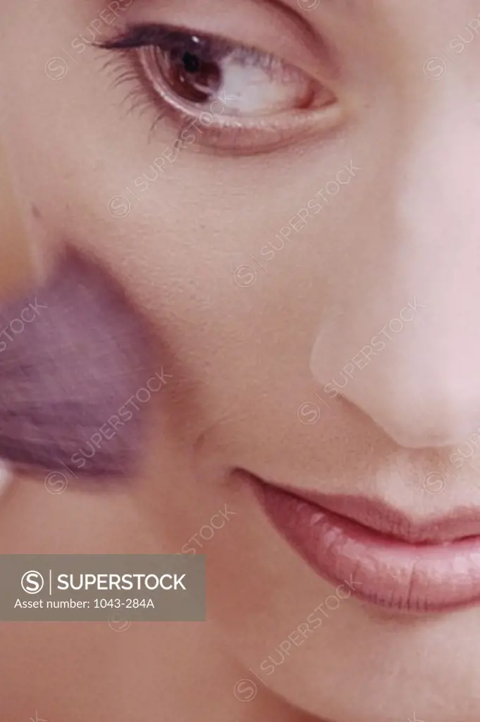 Close-up of a woman applying blush