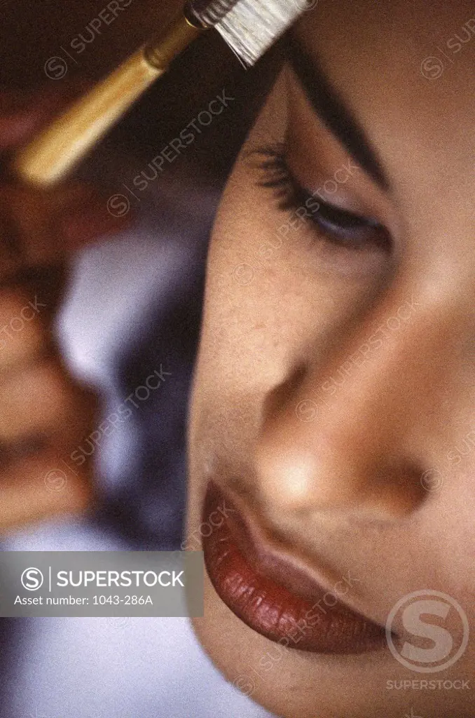 Close-up of a young woman combing her eyebrows