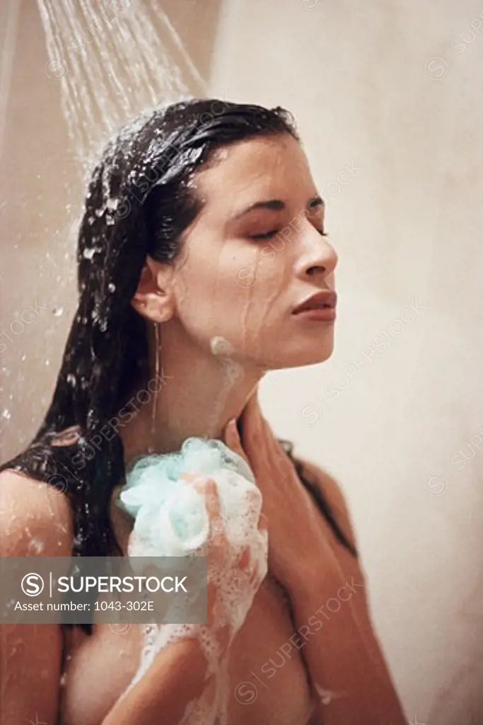 Young woman using a bath sponge in the shower