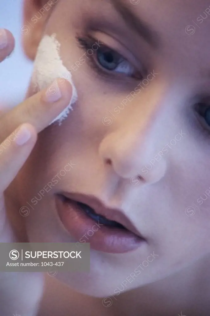 Young woman applying lotion to her face
