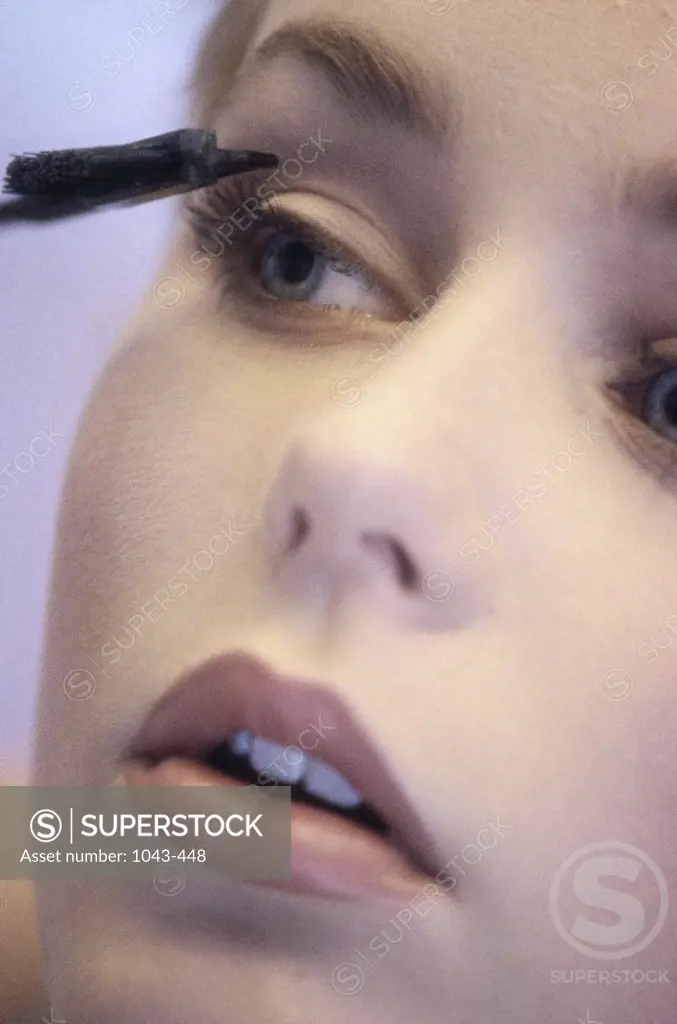 Close-up of a young woman applying eye make-up