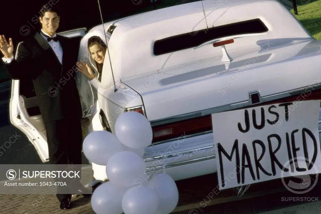 Newlywed couple waving while getting into a car
