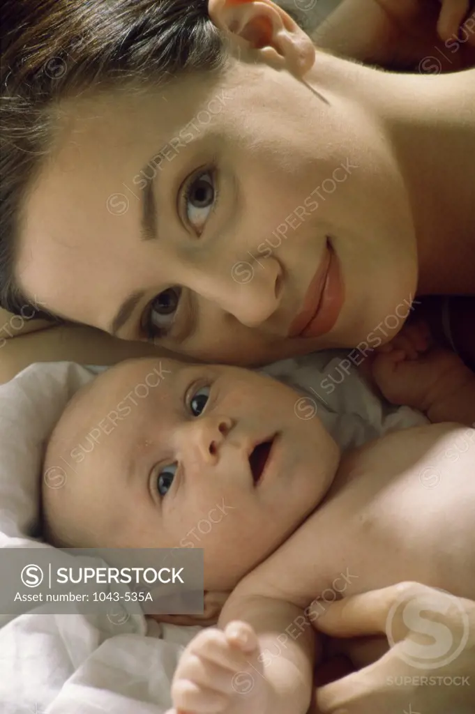 Portrait of a mother lying on a bed with her baby boy