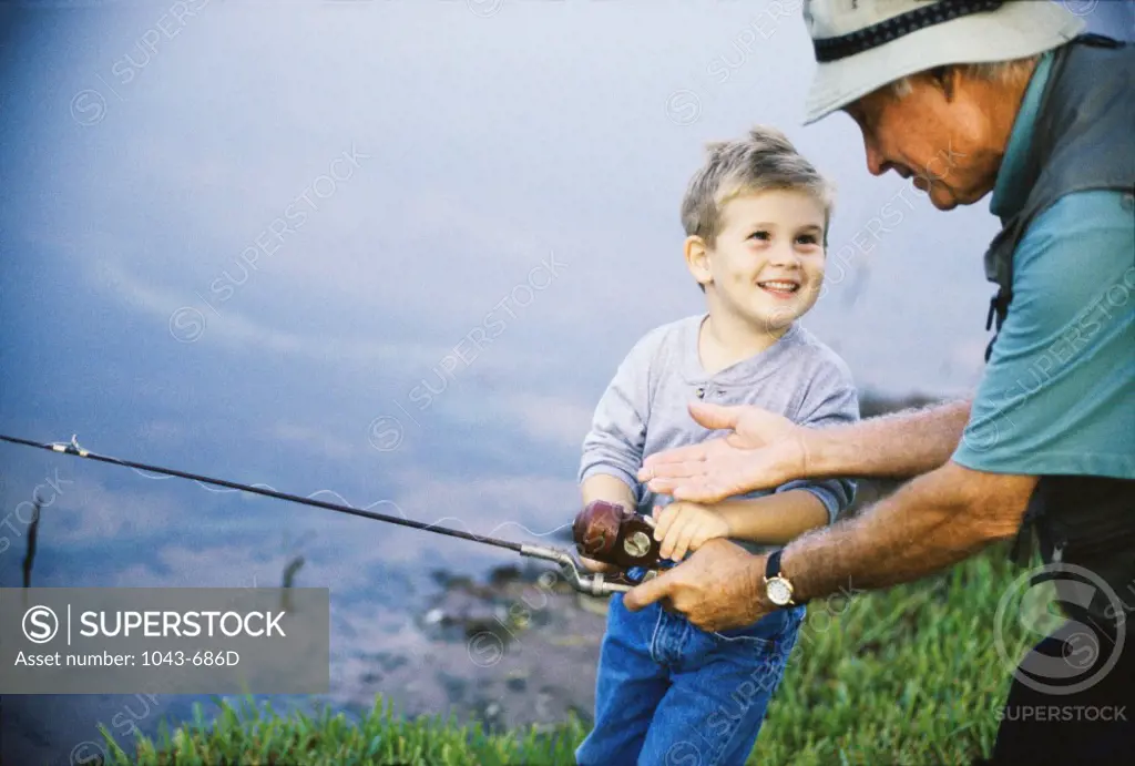 Side profile of an elderly man teaching his grandson how to fish