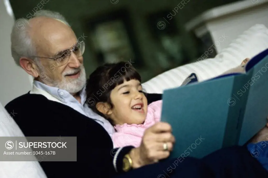 Grandfather reading a book with his granddaughter