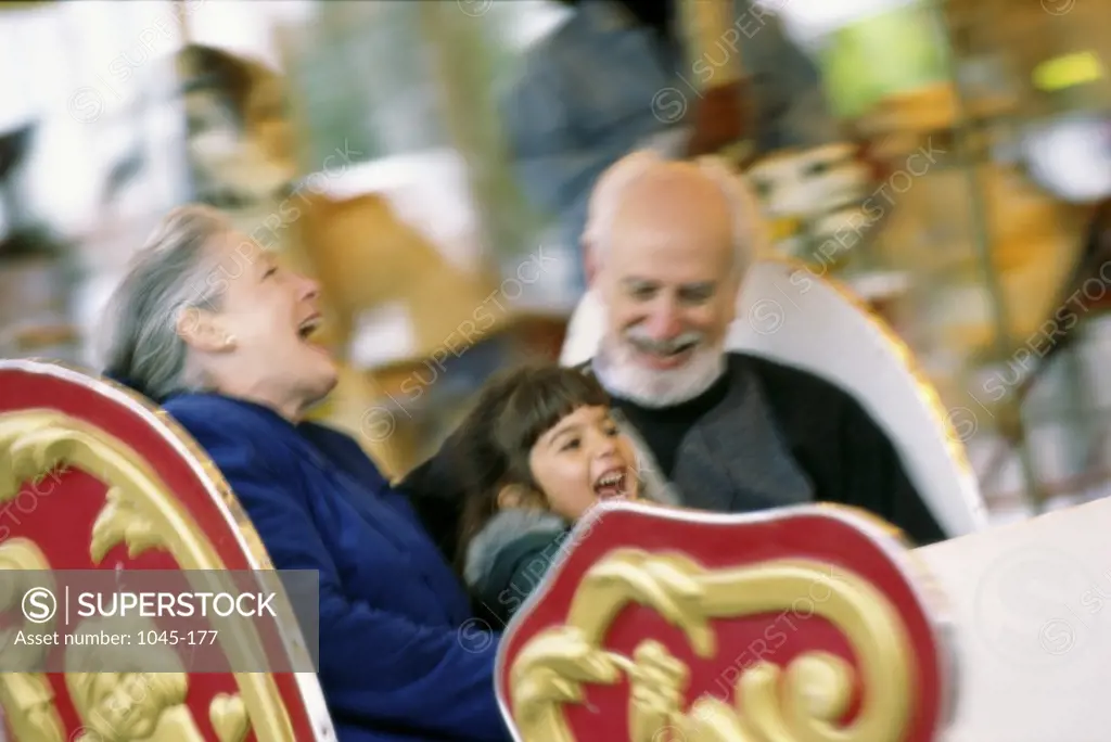 Granddaughter with her grandparents riding a merry-go-round