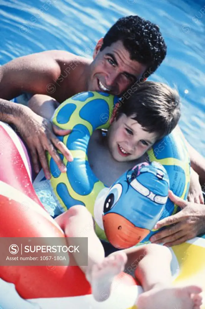 Portrait of a mid adult man with his son in a swimming pool and smiling
