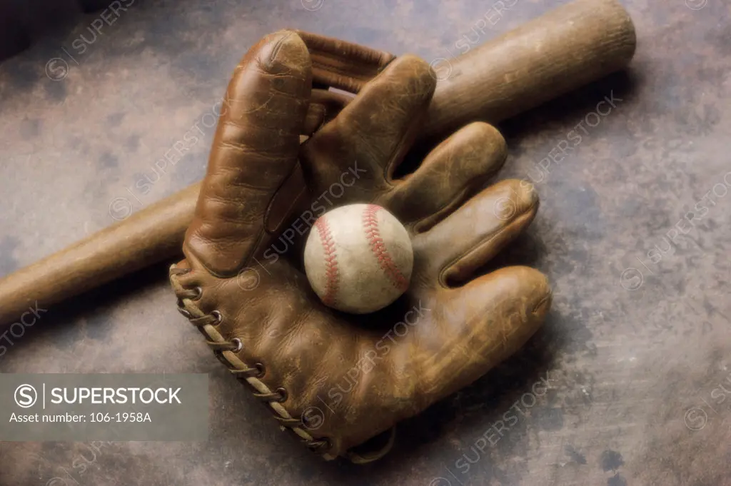 Close-up of a baseball glove with a baseball bat and a ball