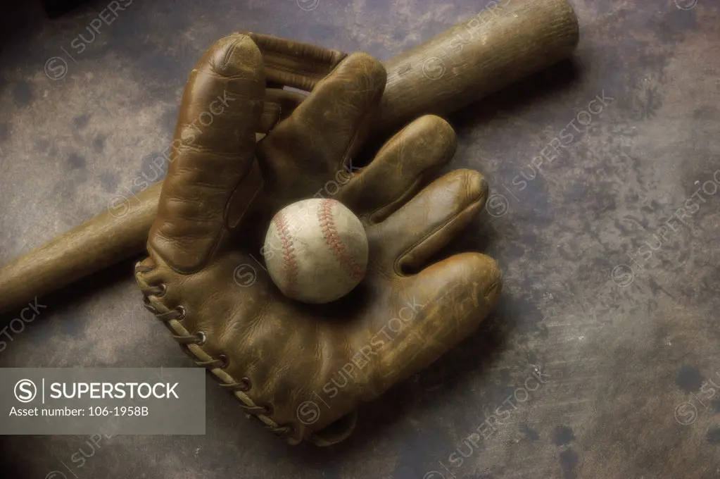 Close-up of a baseball glove with a baseball bat and a ball