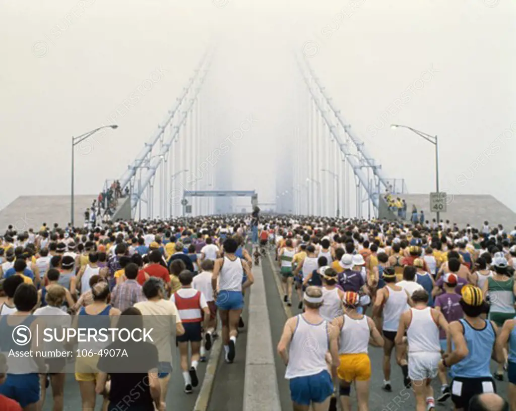 Group of people running in a marathon race on a suspension bridge