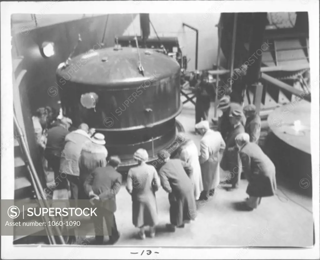 CROWD LOOKING AT NEWLY ALUMINIZED 100-INCH MIRROR AS THE TOP OF THE ALUMINIZING TANK IS REMOVED.