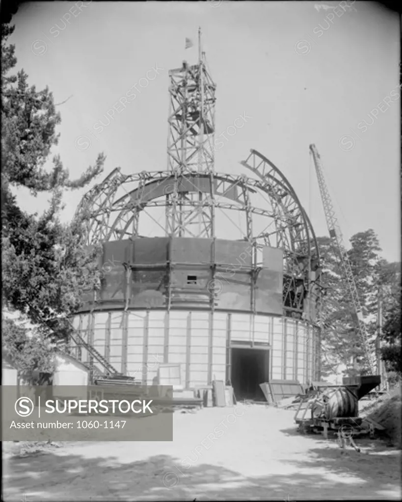 TOP SECTION OF MAIN GIRDER OF 100-INCH TELESCOPE DOME BEING HOISTED THROUGH SHUTTER OPENING; VIEW OF ENTIRE BUILDING.