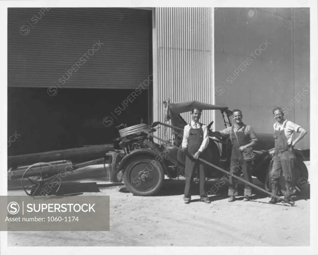 CAR WITH TRAILER CARRYING WOOD TELEPHONE? POLE IN FRONT OF 100-INCH TELESCOPE BUILDING WITH THREE MEN.