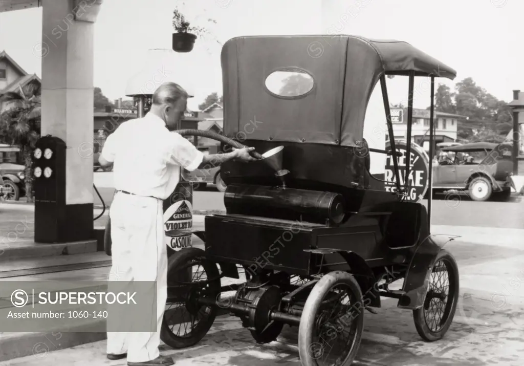 Rear view of a gas station attendant filling up a 1900 Pierce-Arrow, 1929