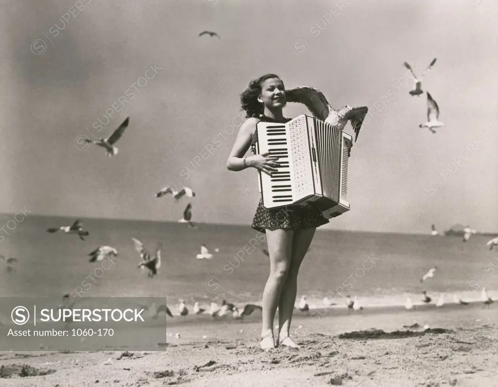 Woman playing the accordion on the beach