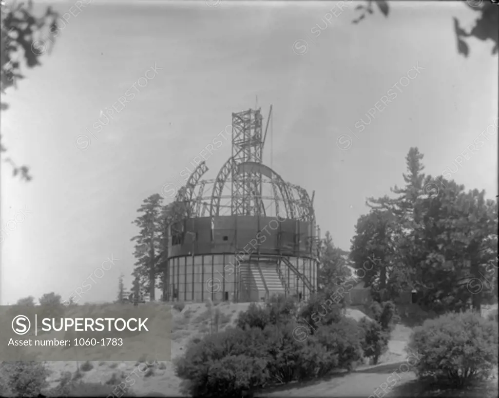 100-INCH TELESCOPE DOME BEING ERECTED WITH CRANE BASE EXTENDING FROM INSIDE THE BUILDING TO WELL ABOVE THE TOP OF THE DOME.