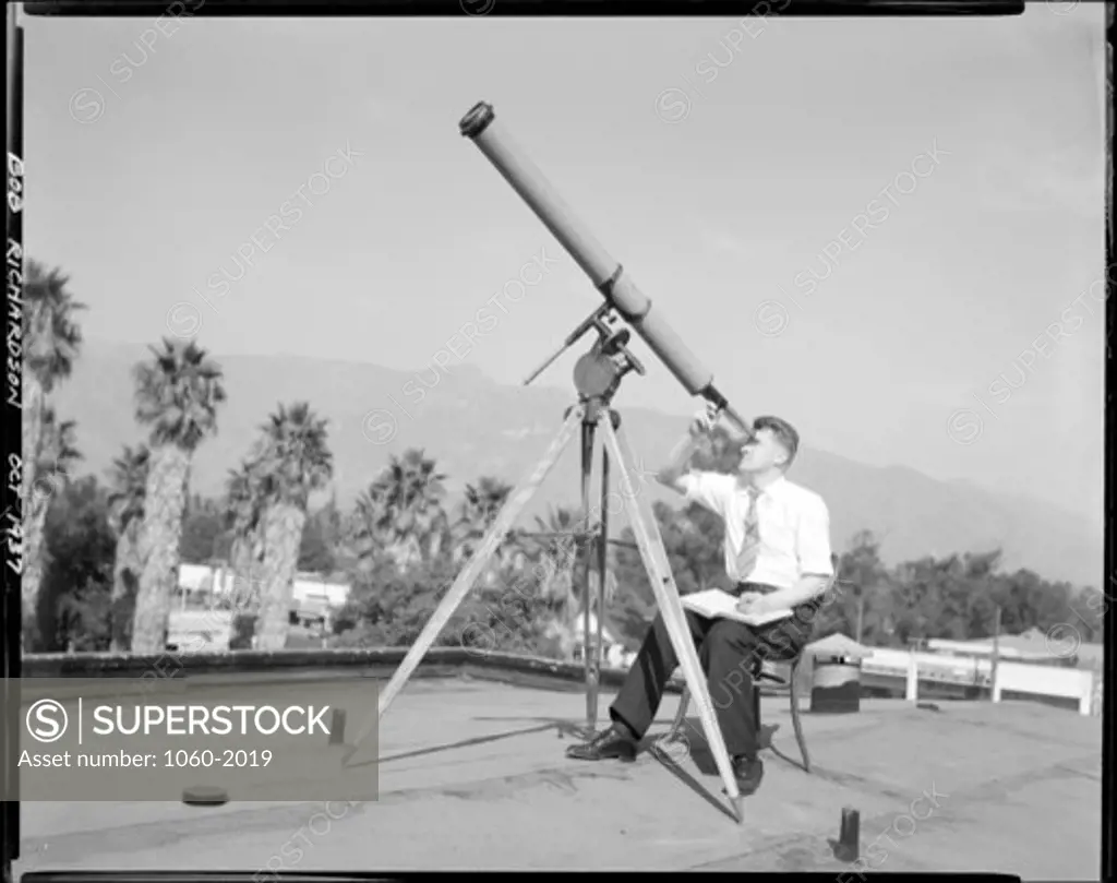 ROBERT RICHARDSON LOOKING THROUGH SMALL REFRACTING TELESCOPE AT SUN ON TOP OF OLD GOVERNMENT? BUILDING AT SANTA BARBARA STREET.