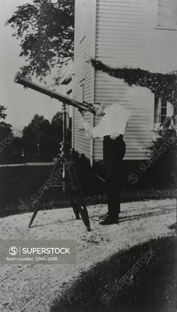 Young Edwin Powell Hubble looking through telescope