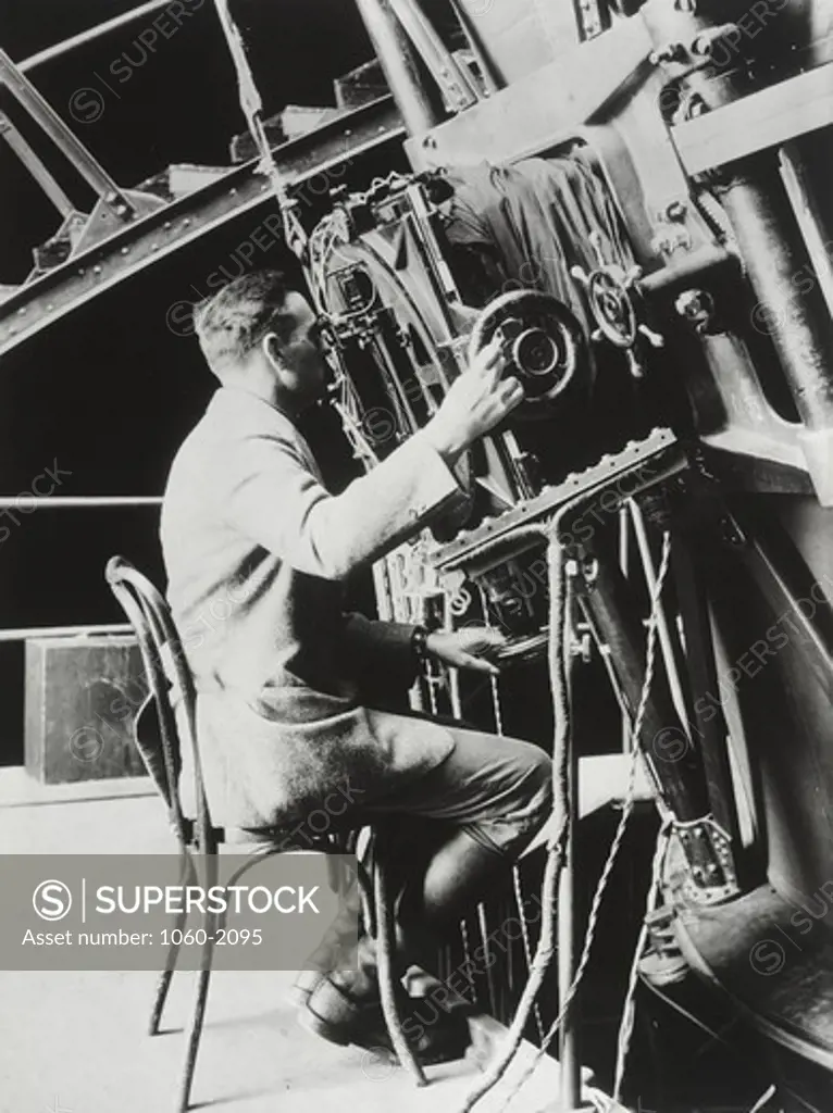 Edwin Powell Hubble sitting in cane chair and looking through hundred inch Hooker telescope