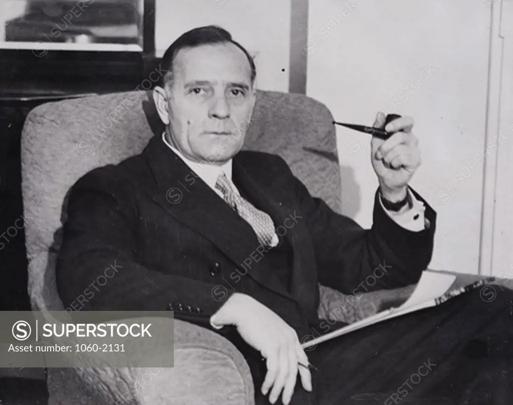 Portrait of Edwin Powell Hubble seated in chair with pipe