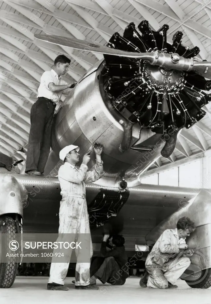 Low angle view of three mechanics assembling a fighter plane in a factory, Delta Fighter, Northrop Corporation, 1933