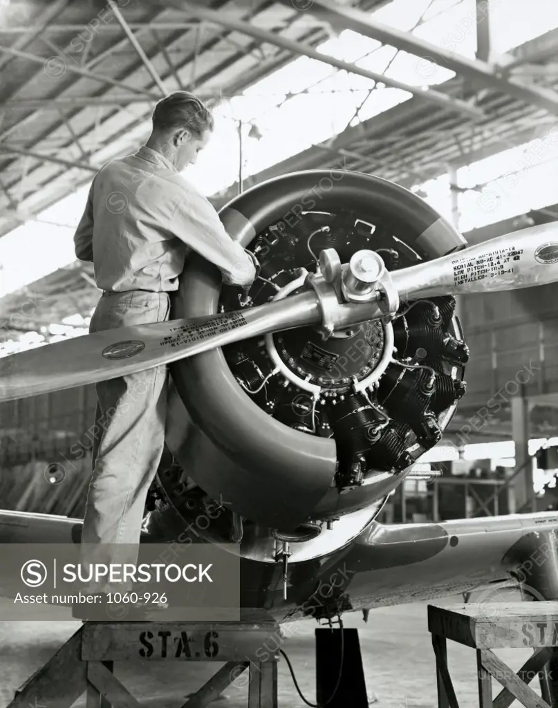 Side profile of a mechanic working on an air craft in an assembly plant, Vultee Aircraft, 1940