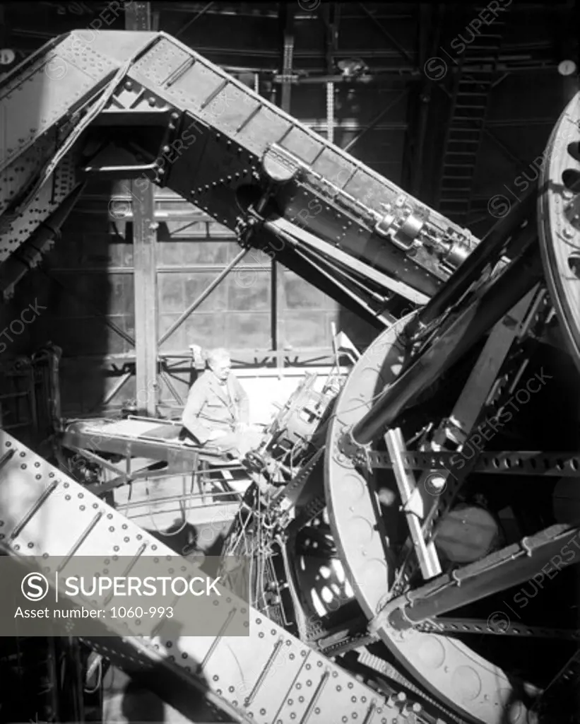 FRANCIS PEASE SEATED AT THE CASSEGRAIN FOCUS OF THE 100-INCH TELESCOPE; TUBE IS TIPPED AWAY FROM PEASE.