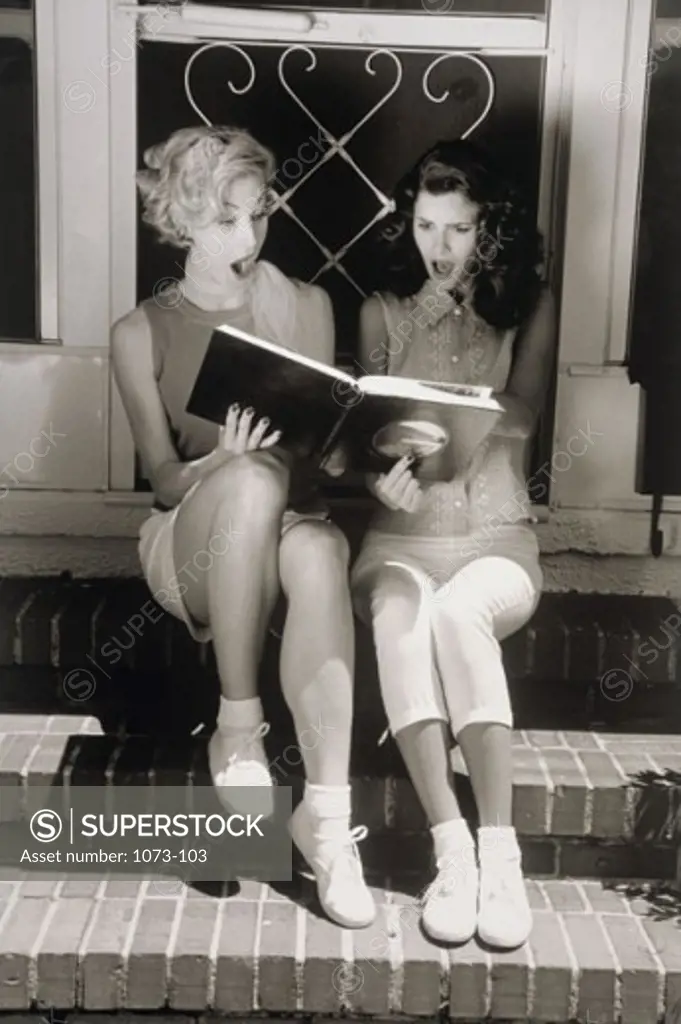 Two young women looking at photo album