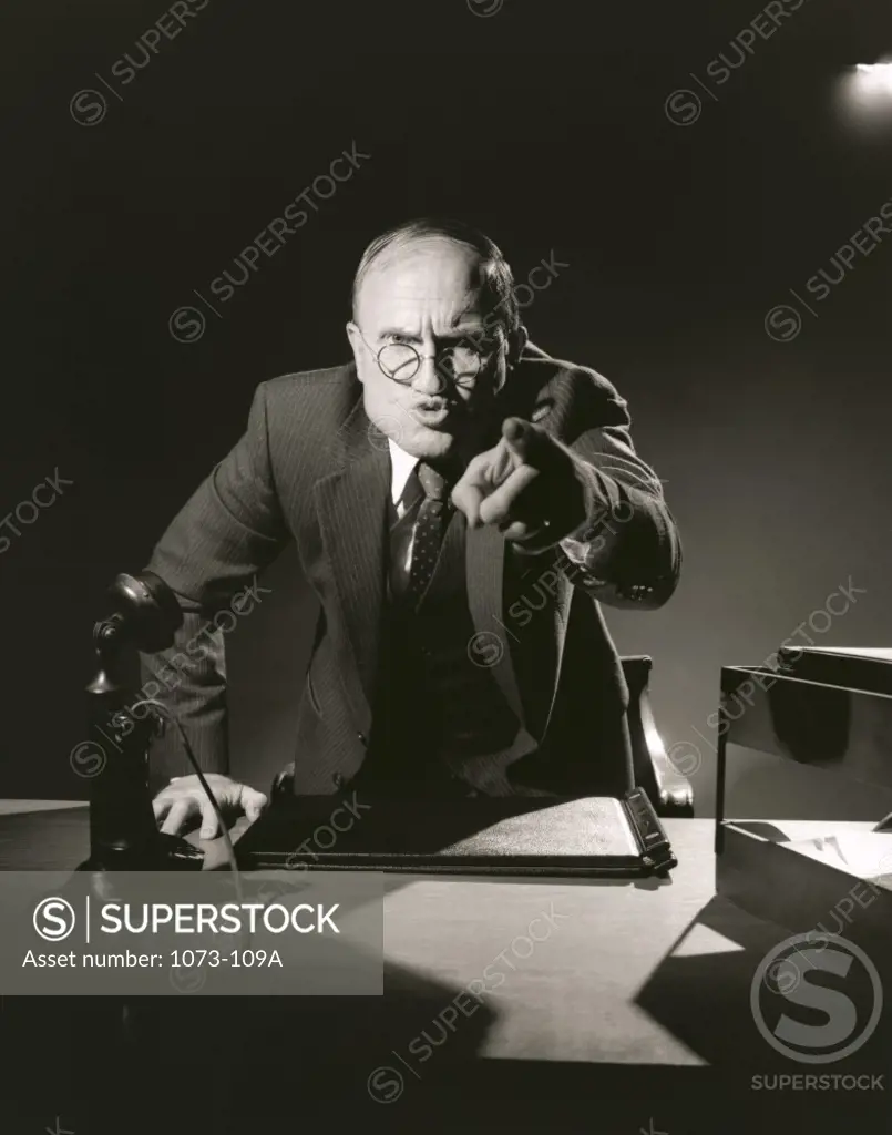 Businessman pointing to camera in office