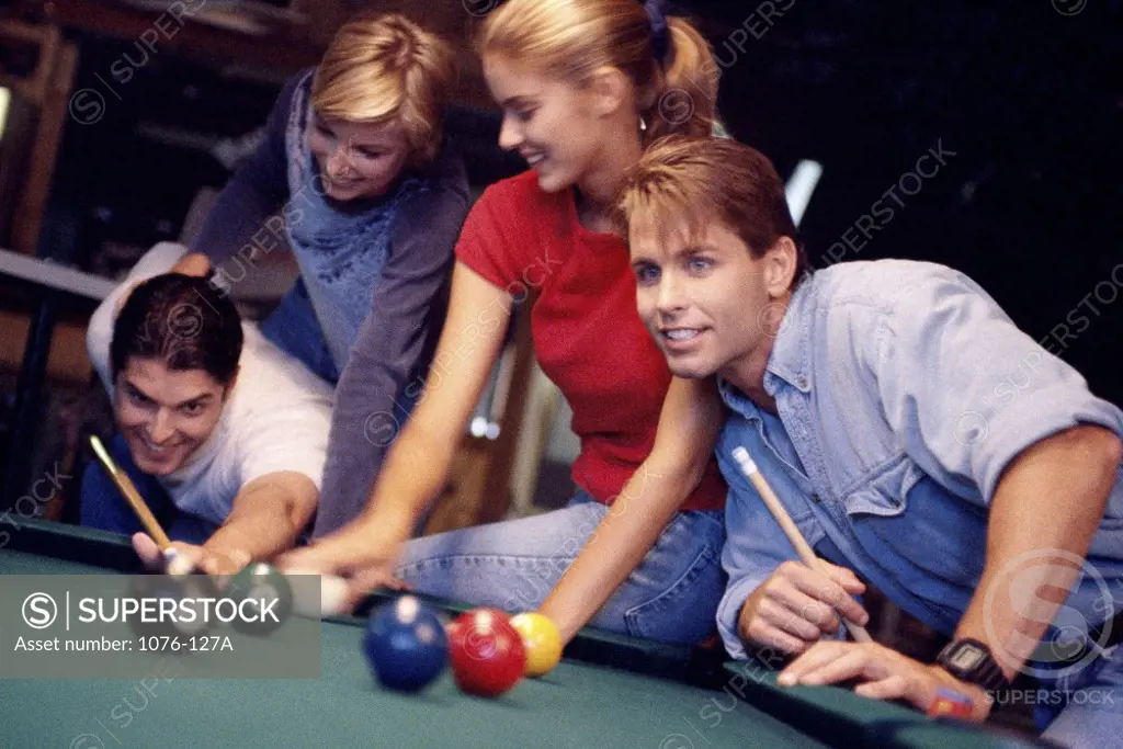 Two young couples playing pool
